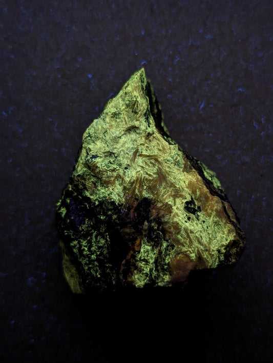 A rough, irregularly shaped mineral specimen with a textured surface displaying patches of vibrant green and dark brownish-black.
