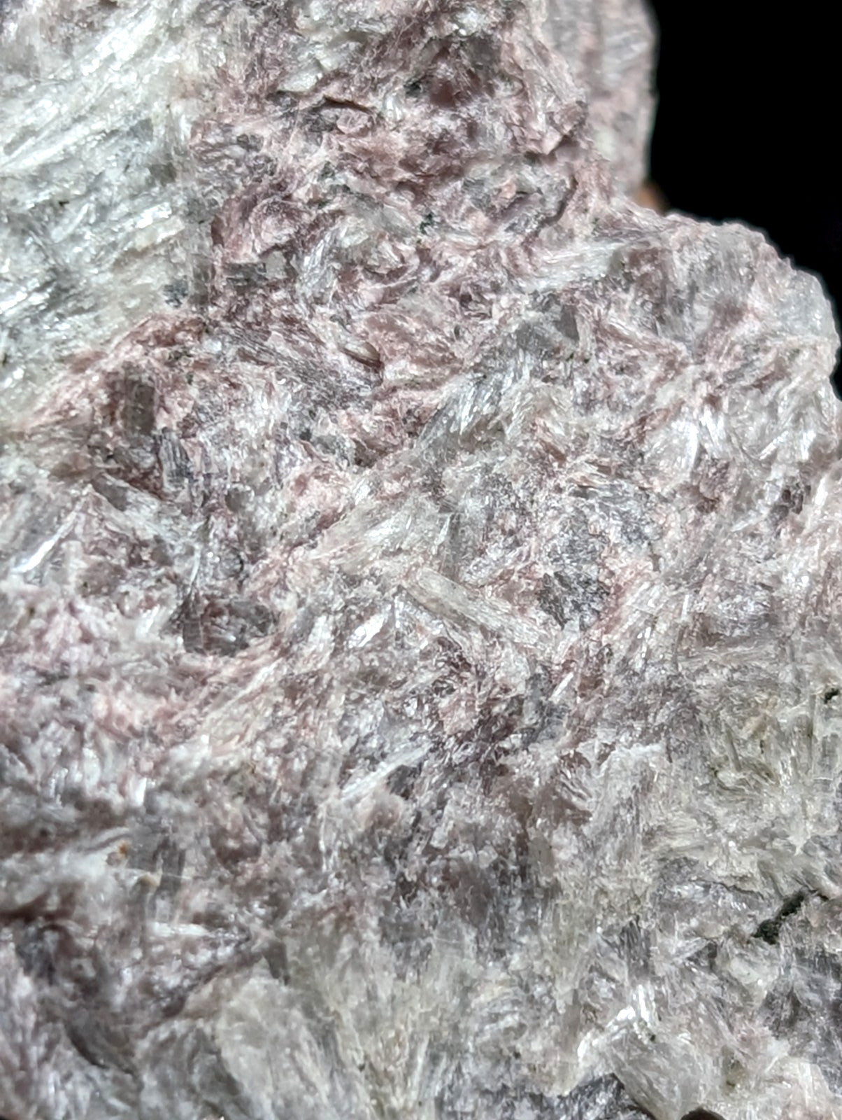 A rough, translucent mineral specimen with a crystalline texture and intermingled grayish-white and faint pink hues.