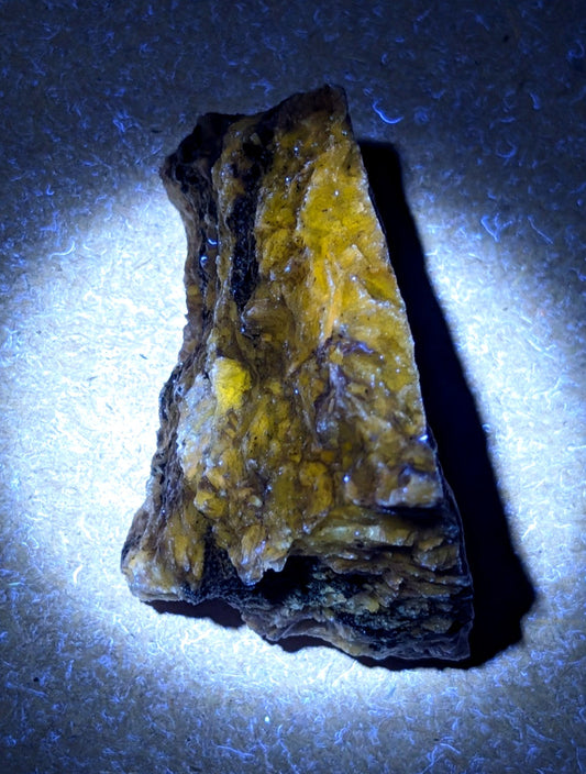 A rugged, irregularly shaped piece of yellow and black mineral with a crystalline texture.