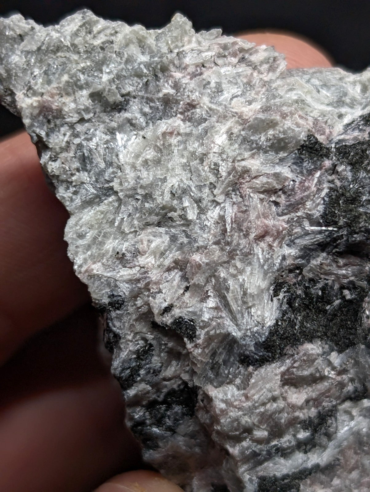 A rough, irregularly shaped mineral specimen with a mix of silvery-white crystalline textures and dark gray to black patches.