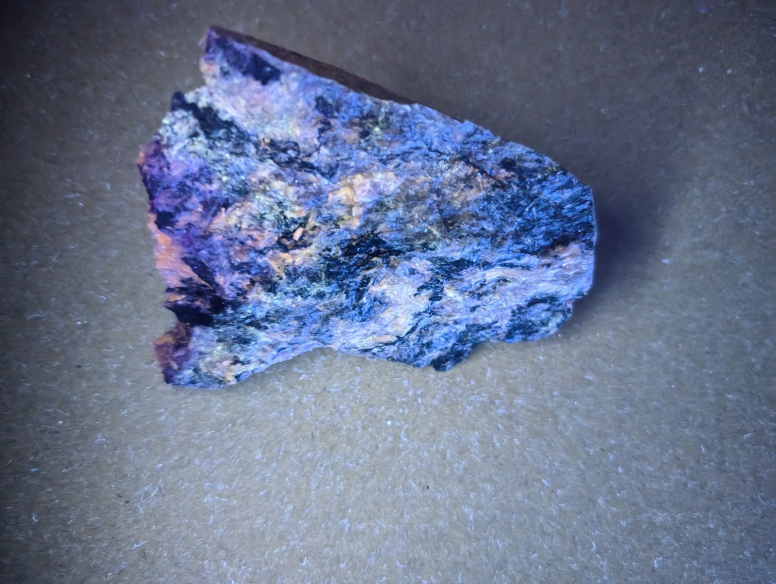 A rugged, irregularly shaped piece of mineral with a vibrant blue base and streaks of purple, pink, and white.