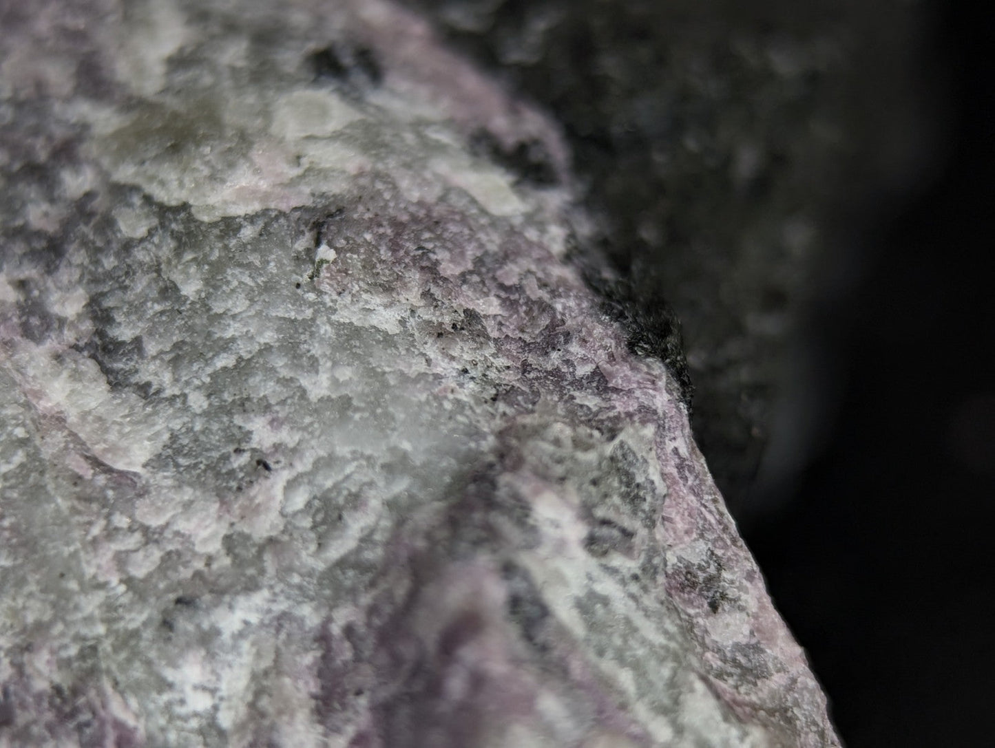 A textured, mottled rock with a mix of gray and subtle pinkish hues.