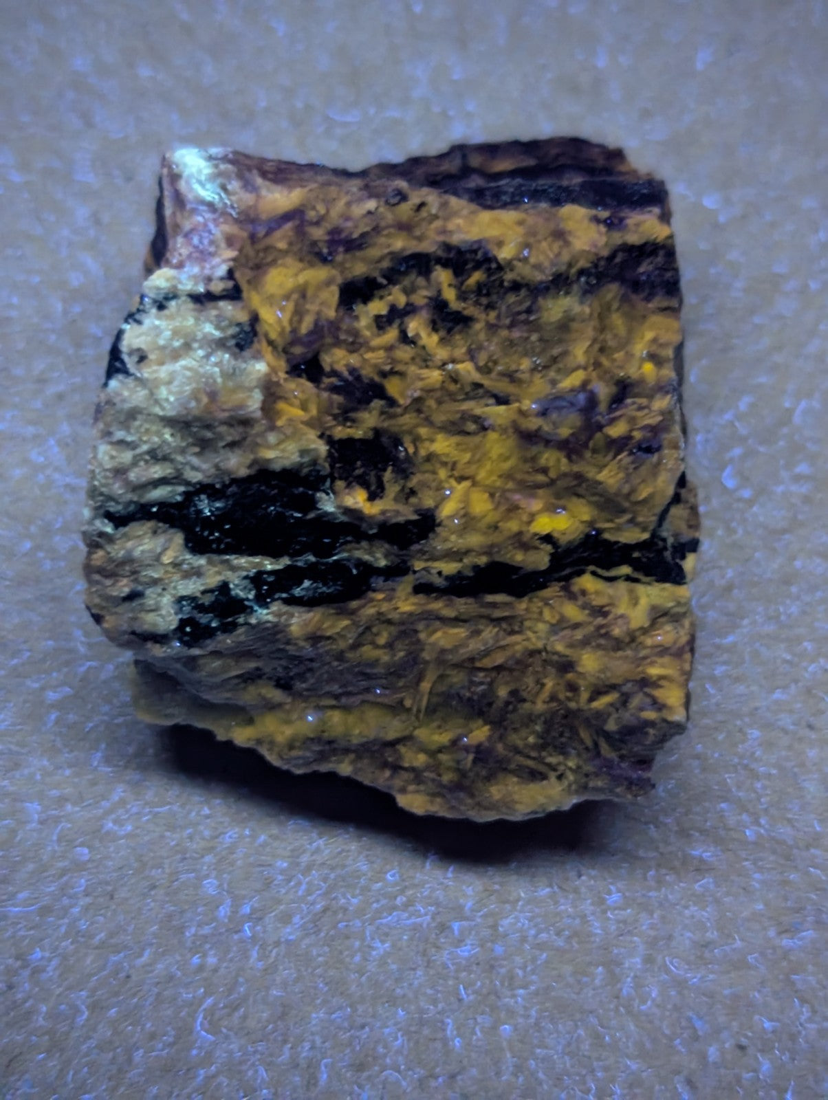 A rugged, irregularly shaped piece of yellow and black mineral with a rough, textured surface.