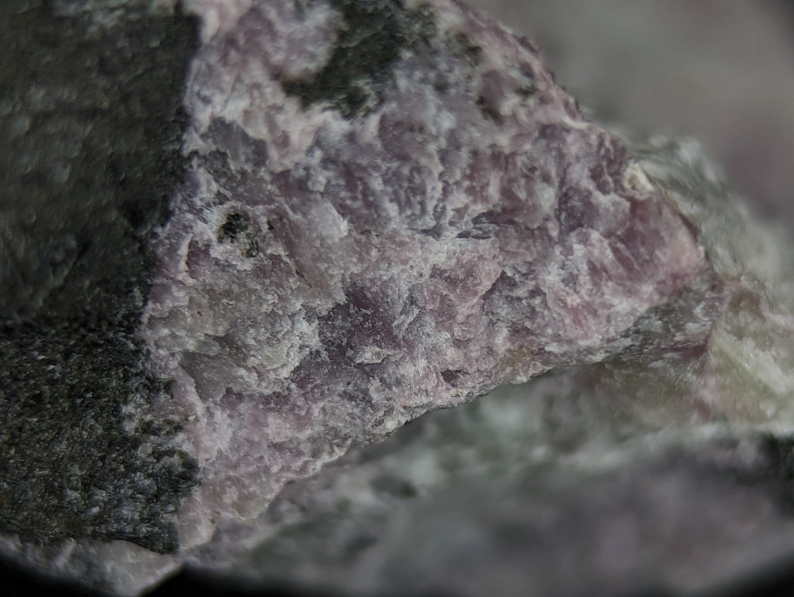 A rough, naturally occurring mineral specimen with a mottled pink and gray surface texture.