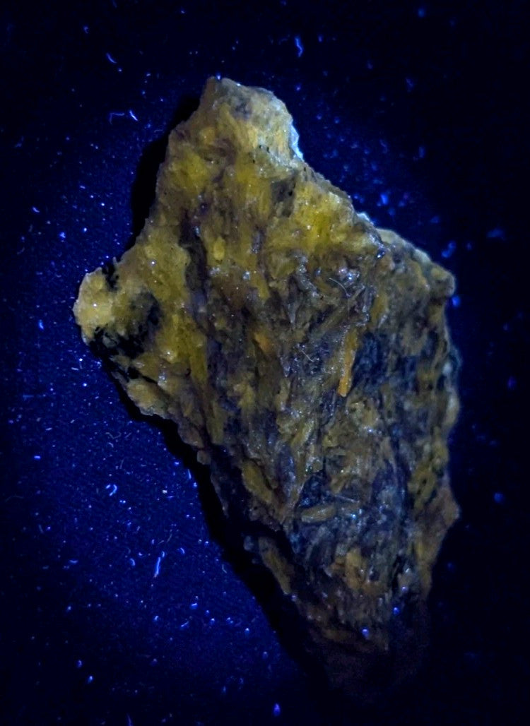 A rugged, irregularly shaped mineral specimen with a textured surface displaying patches of vibrant yellow and dark earthy tones.