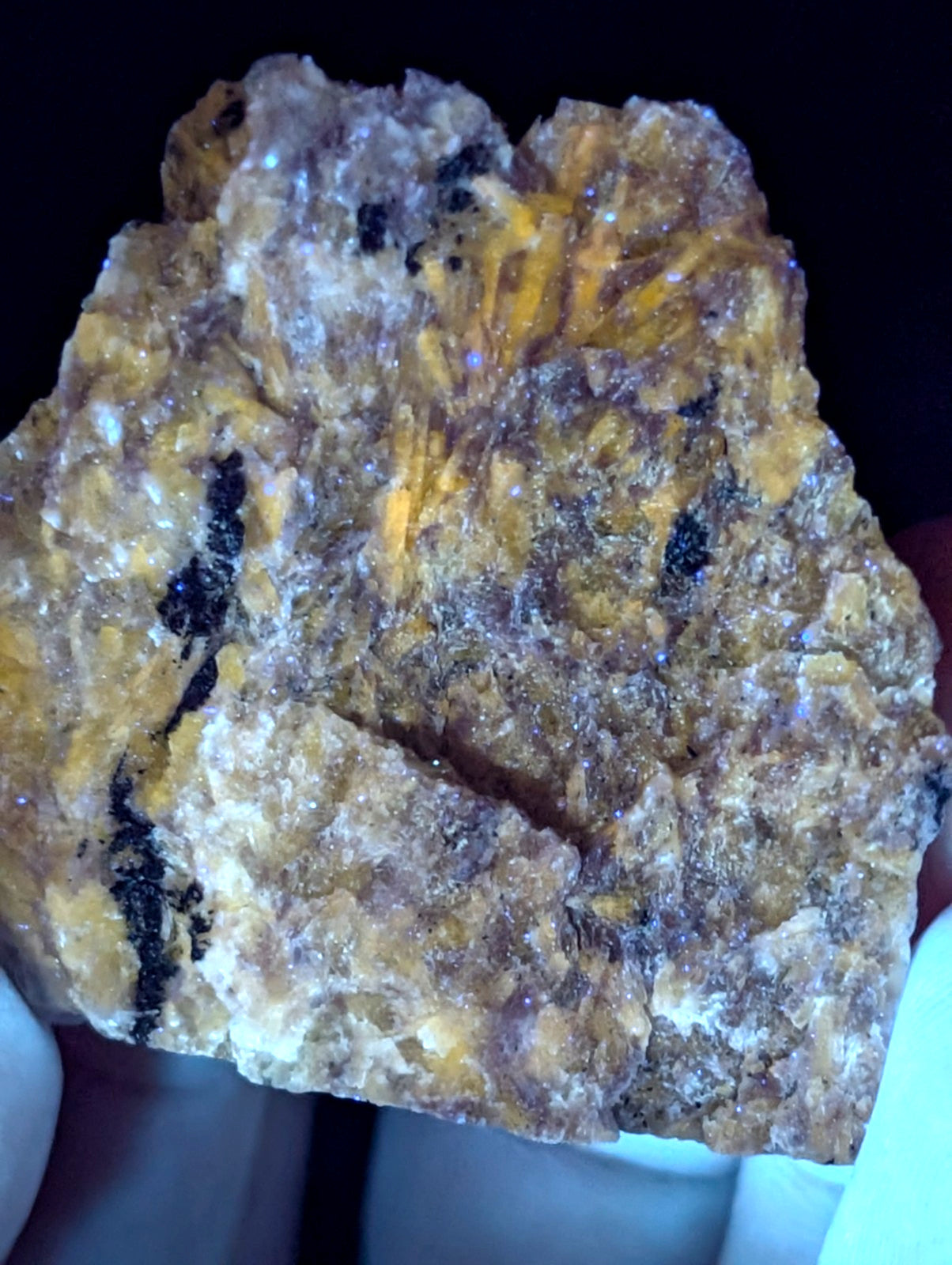 A rugged, irregularly shaped mineral specimen with a textured surface displaying vibrant yellow and brown hues interspersed with dark black streaks.