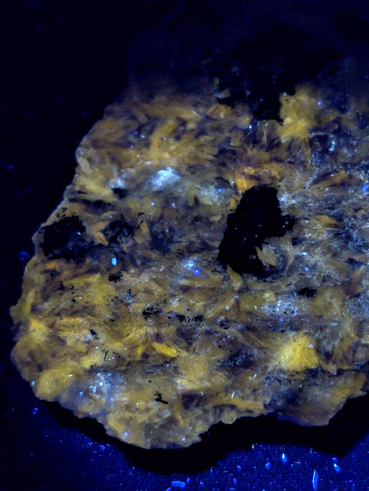 A rugged, irregularly shaped mineral specimen with a translucent yellowish-gold hue and embedded dark inclusions.