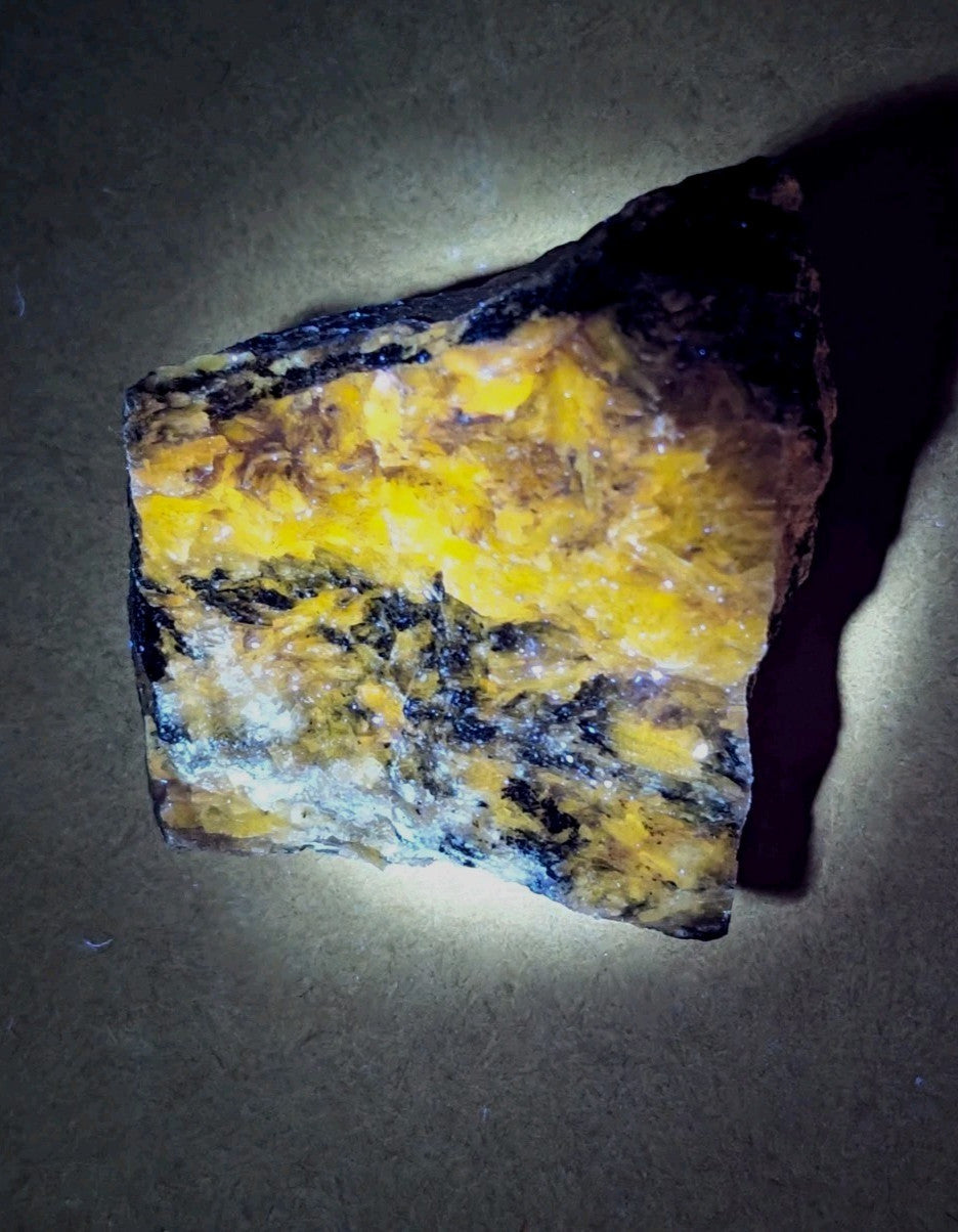 A vibrant yellow and black mineral specimen with a rough, naturally fractured surface.