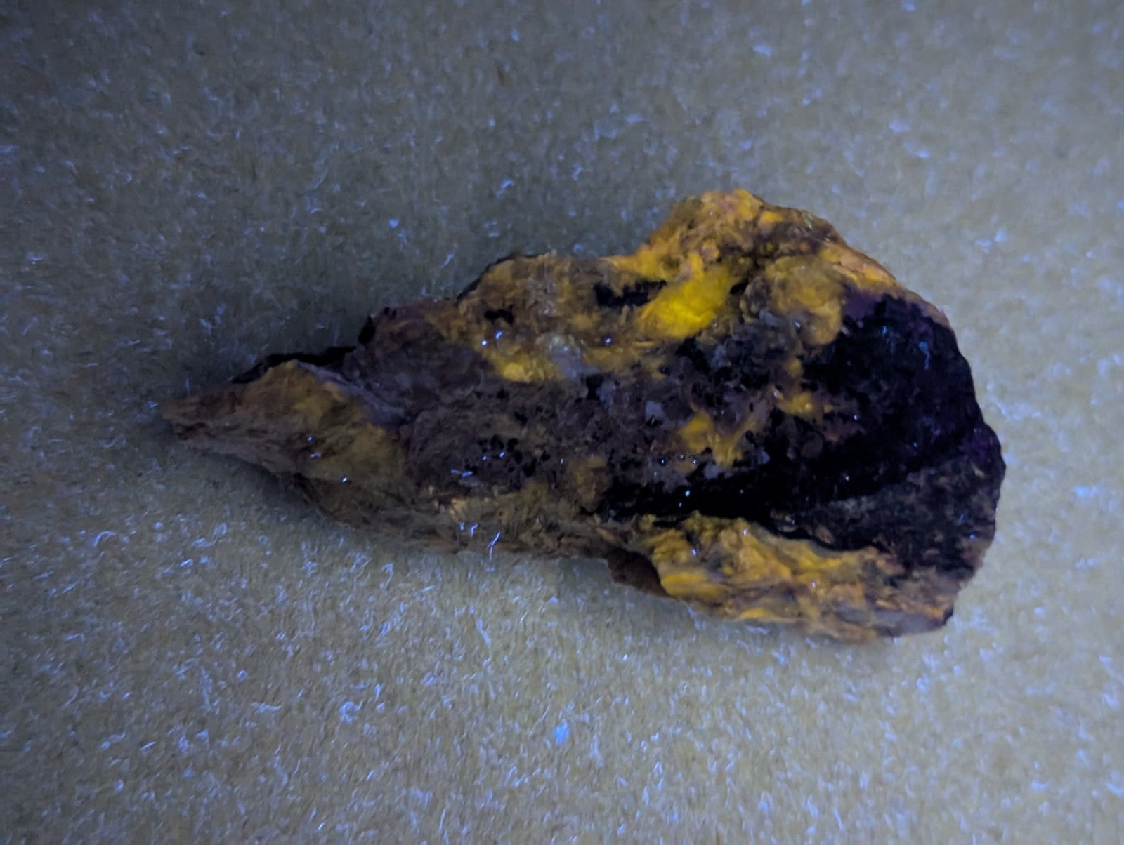 A rugged, irregularly shaped rock with a striking contrast of deep black and vibrant yellow patches.