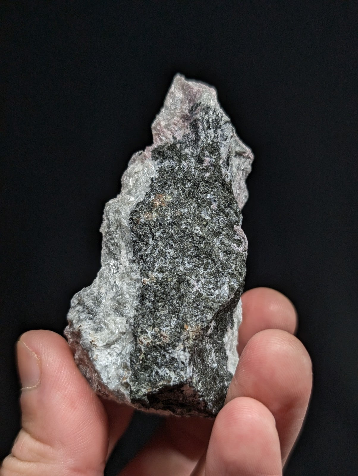 A rough, irregularly shaped gray rock with speckled black and white mineral patterns.