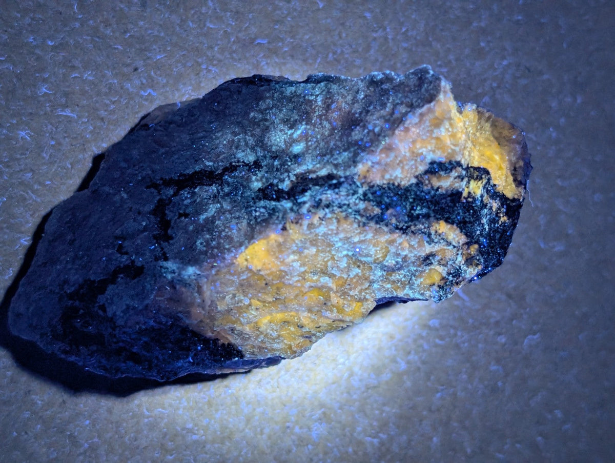 A rugged miserite and wollastonite rock from wilson springs with black yellow and blue green mineral patches