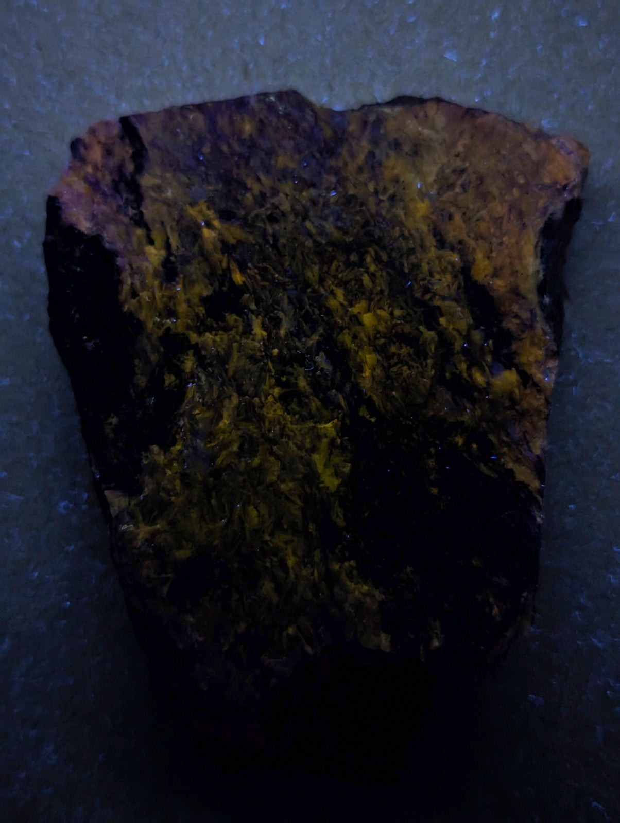 A rugged, irregularly shaped piece of mineral with a dark base and vibrant yellow-green veining.