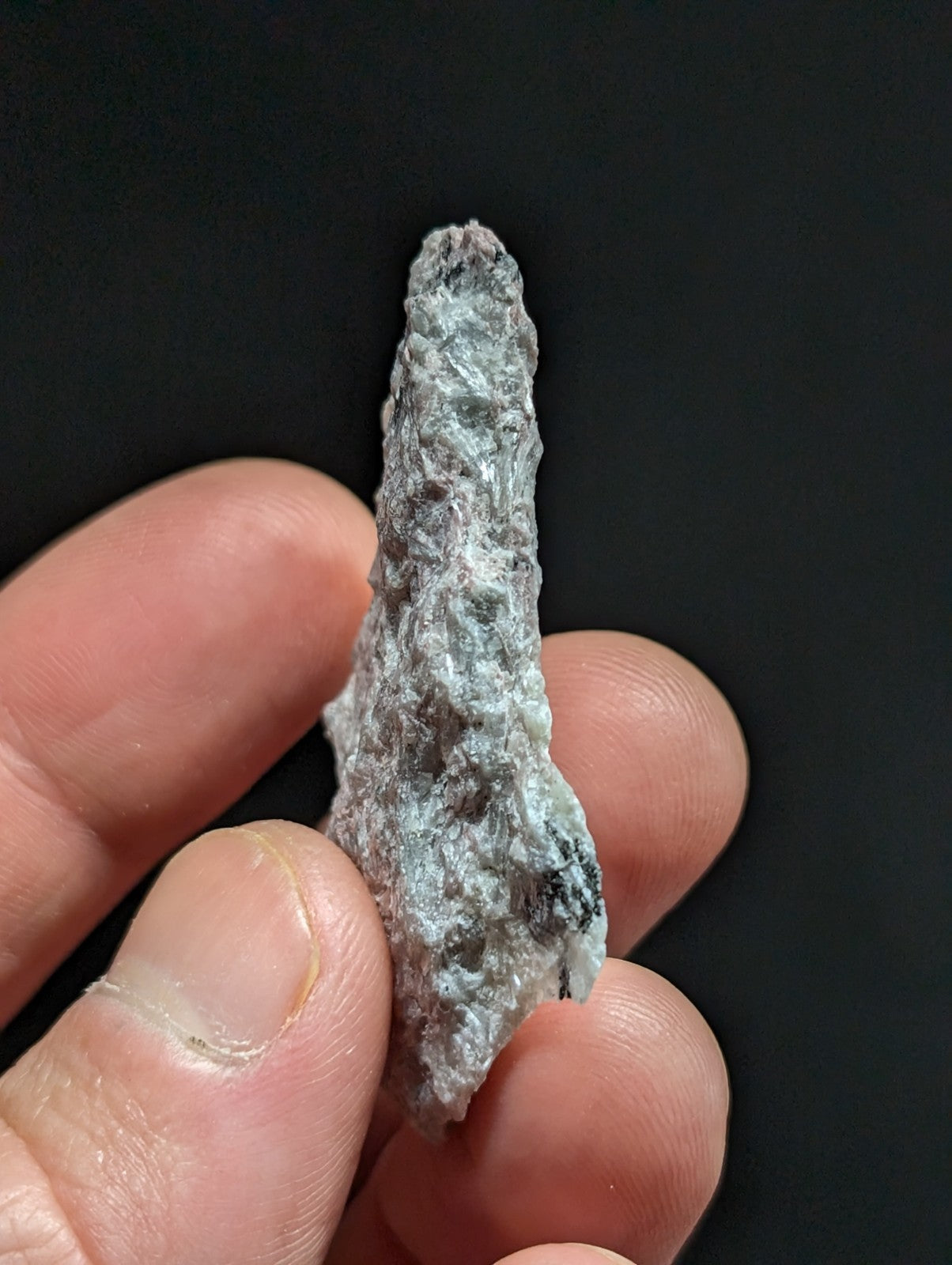 A rough, irregularly shaped mineral specimen with a mottled gray and greenish-blue surface texture.