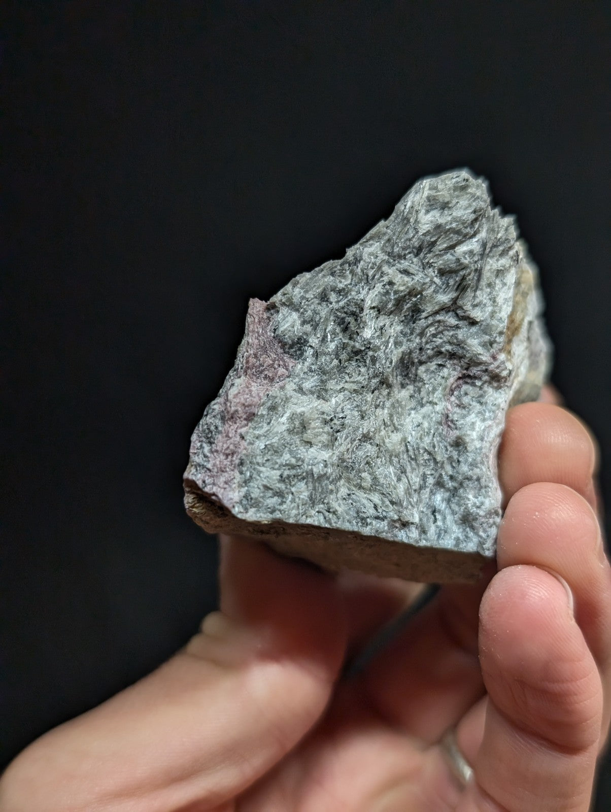 A rough, irregularly shaped gray rock with subtle pinkish and white veining.