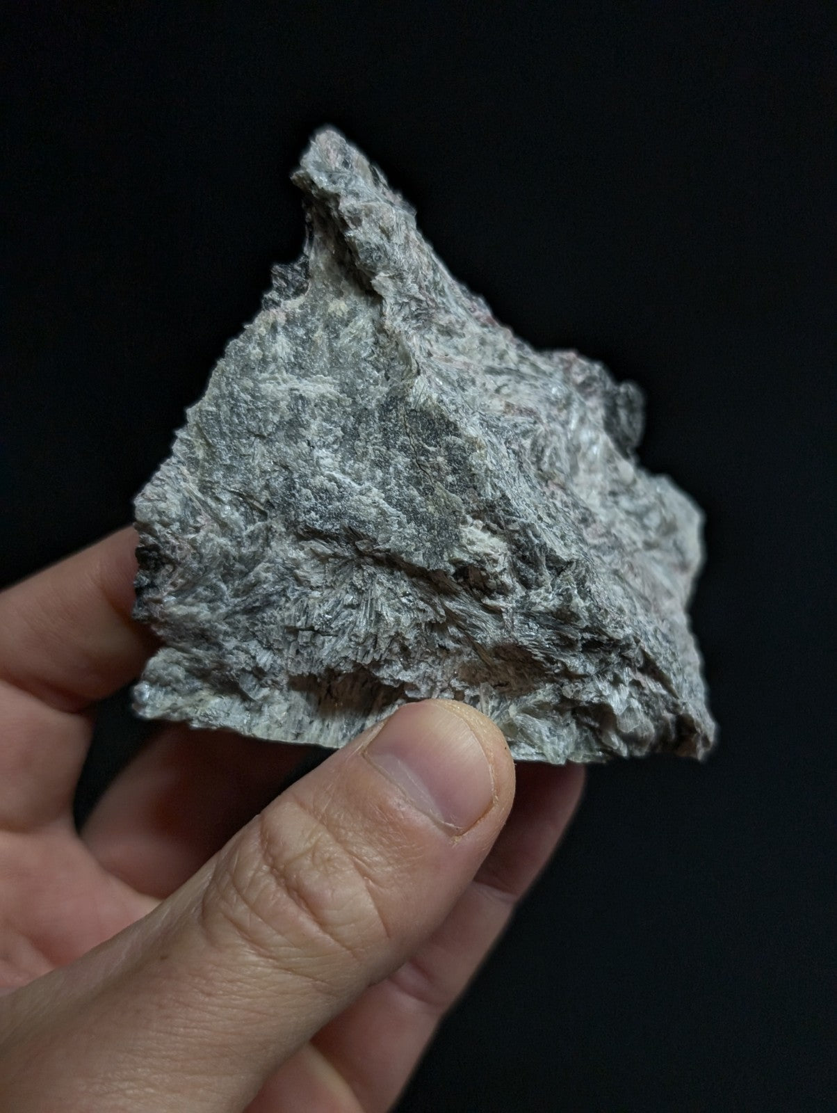A rough, grayish-white mineral specimen with a textured, crystalline surface.