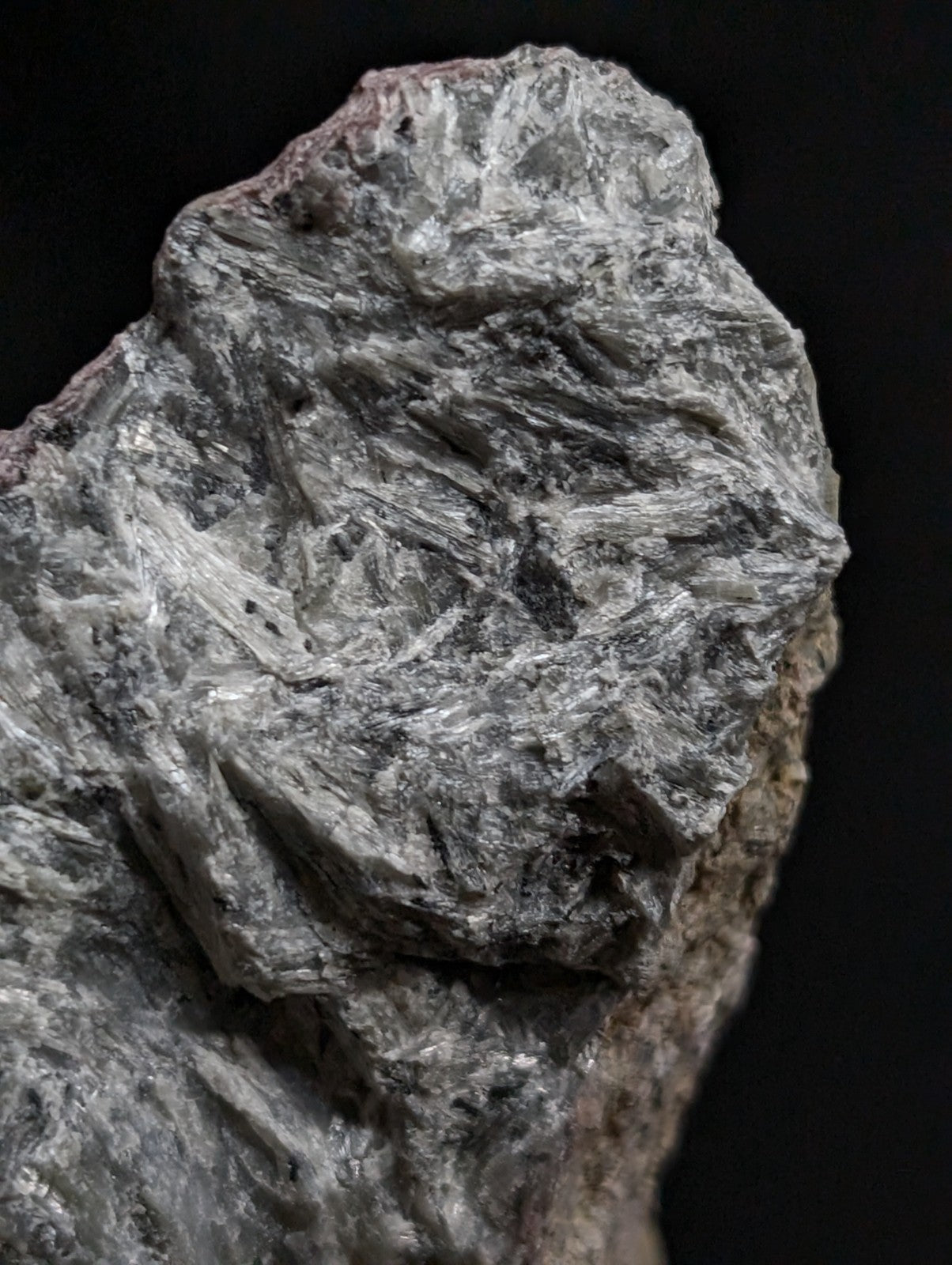 A rough, grayish-white mineral specimen with a textured surface and visible crystalline patterns.