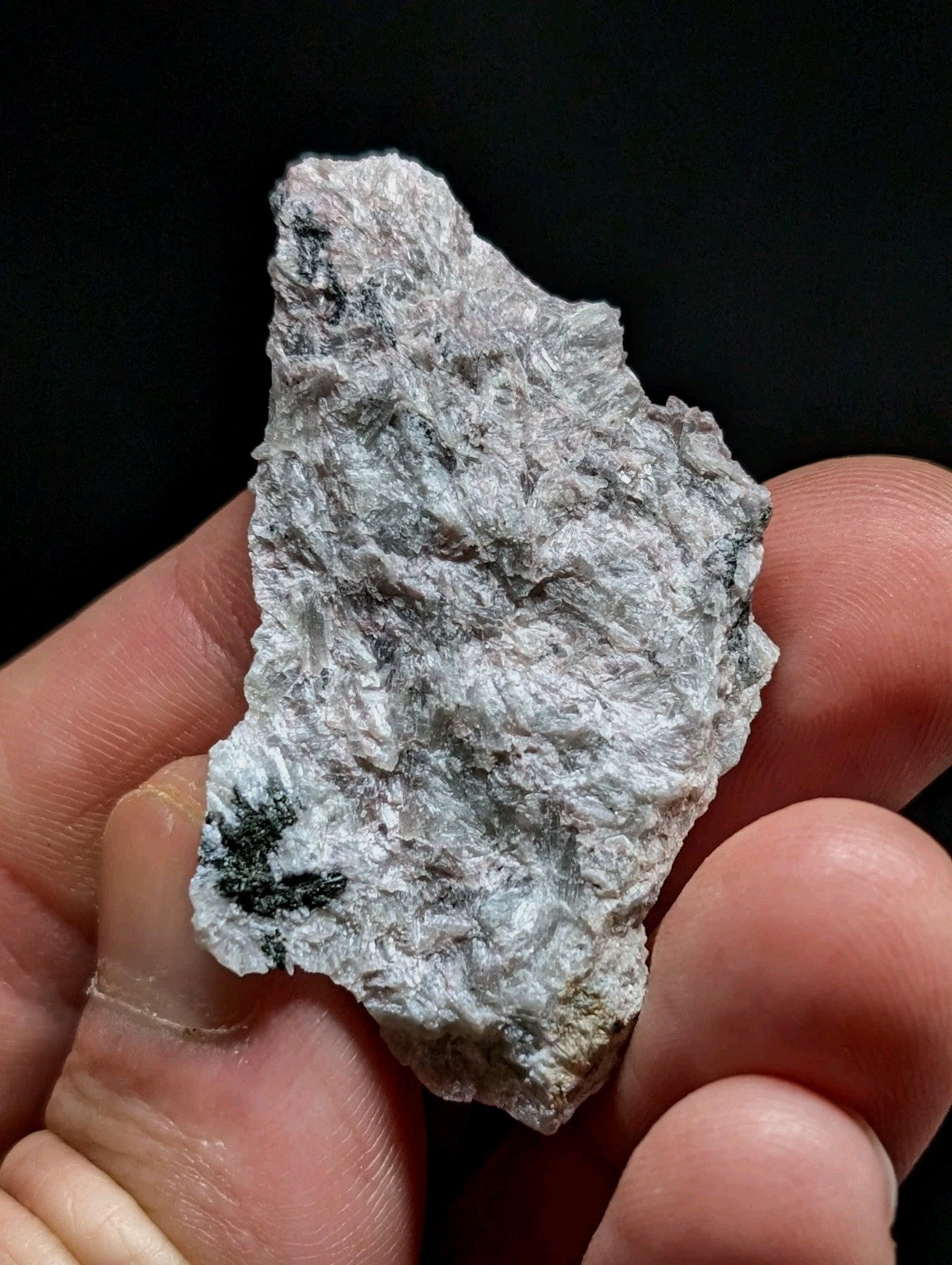 A rough, irregularly shaped piece of light gray rock with subtle greenish-black mineral inclusions.