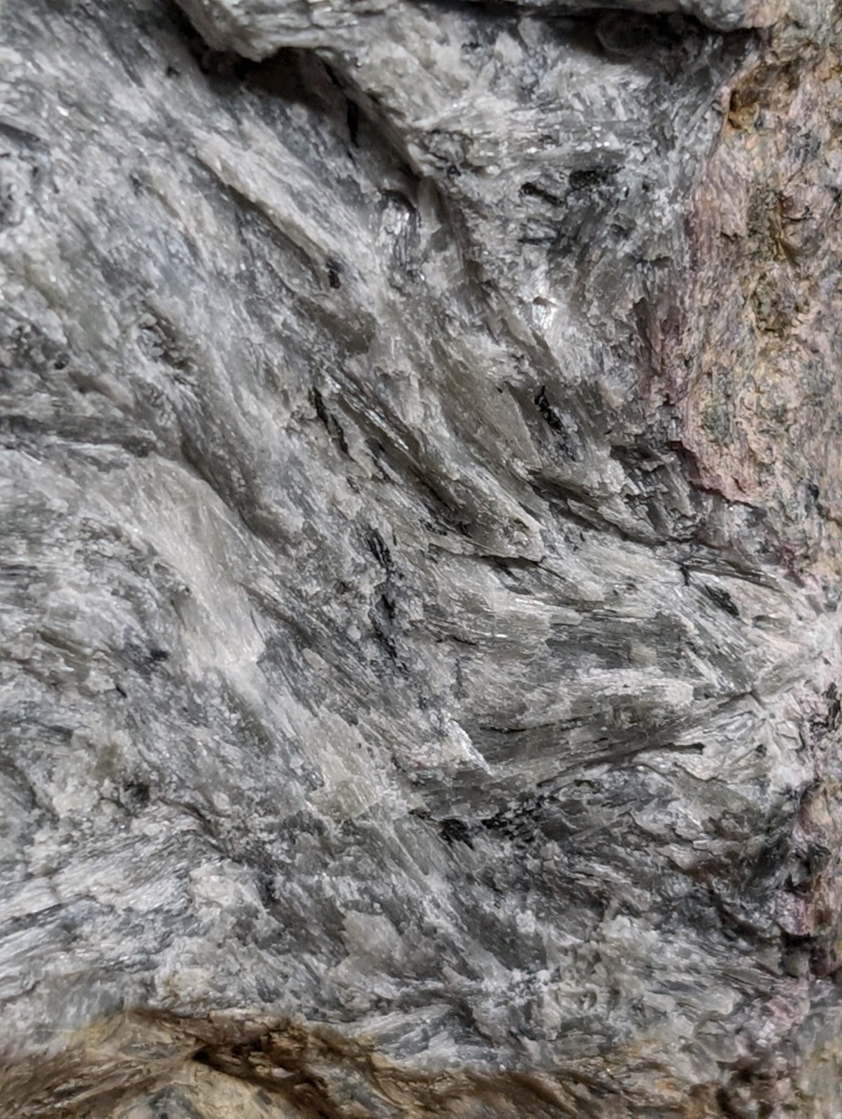 A rugged, grayish-white rock with streaks of black and subtle brown tones.