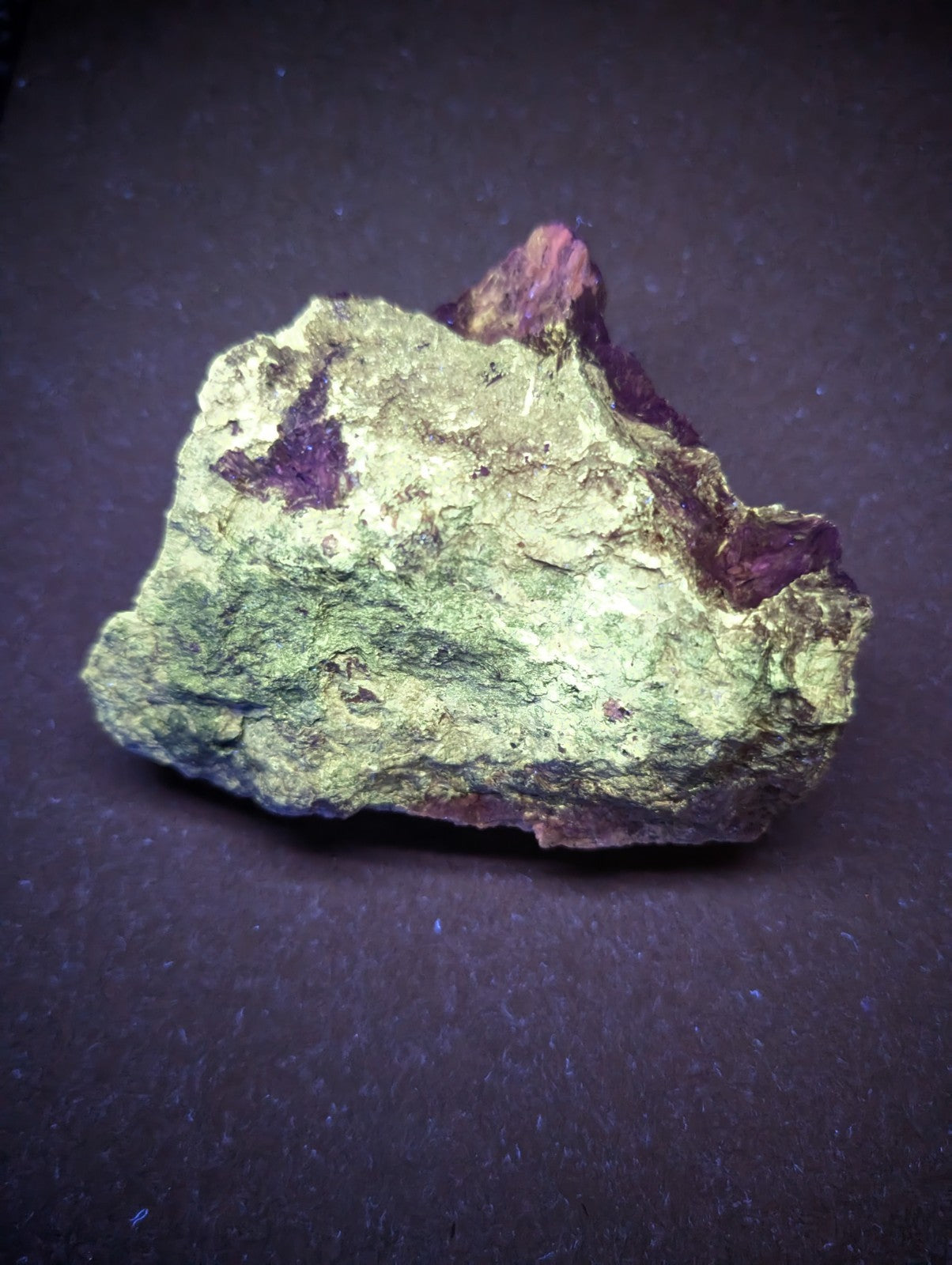 A rough, irregularly shaped mineral specimen with a mottled green and purple surface.