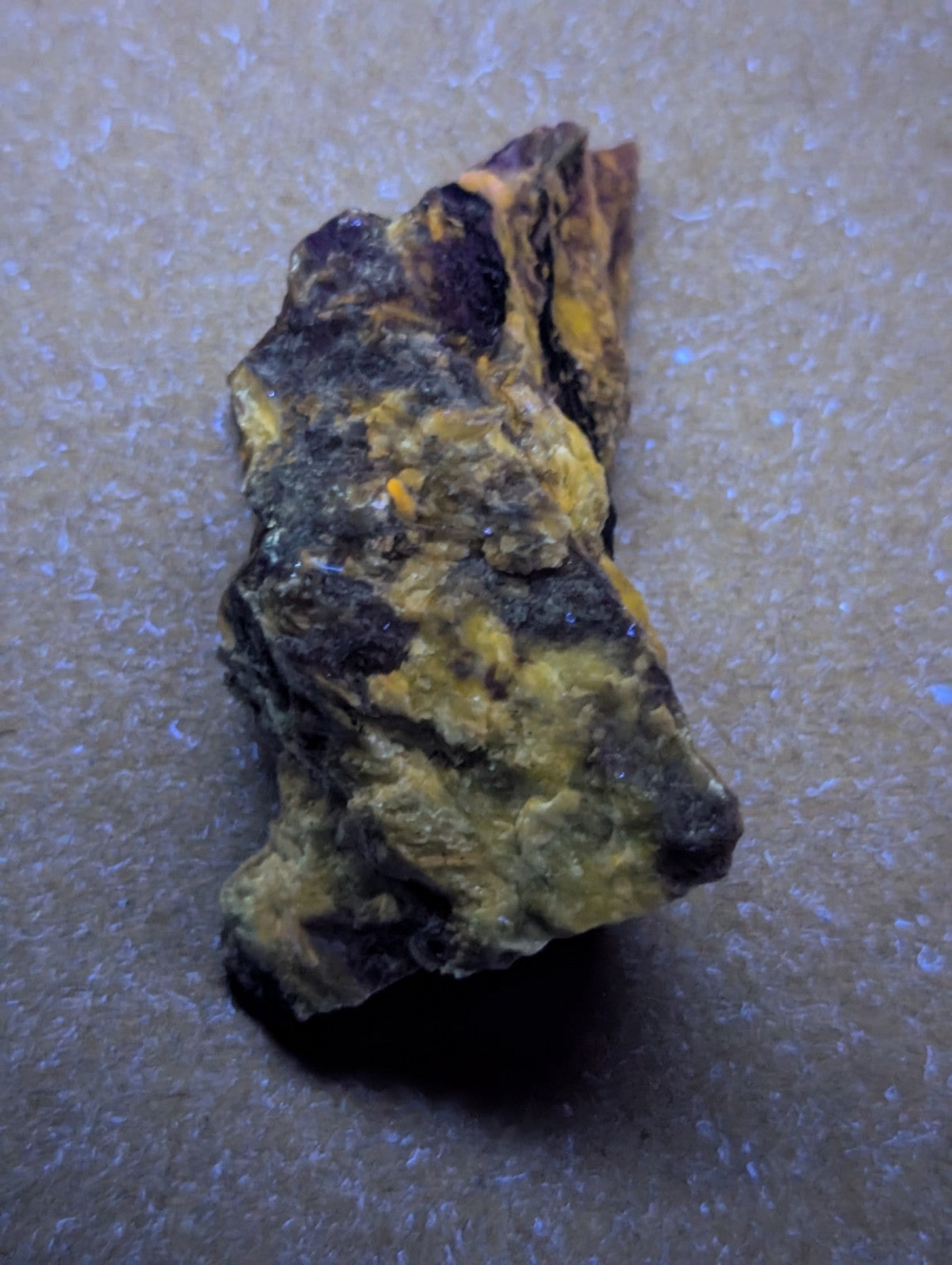 A rugged, irregularly shaped piece of yellow and black mineral rock with a rough, textured surface.