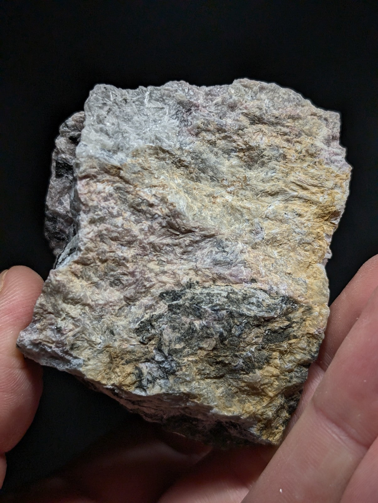 A rough, irregularly shaped rock with a mottled surface of gray, beige, and subtle yellowish tones.