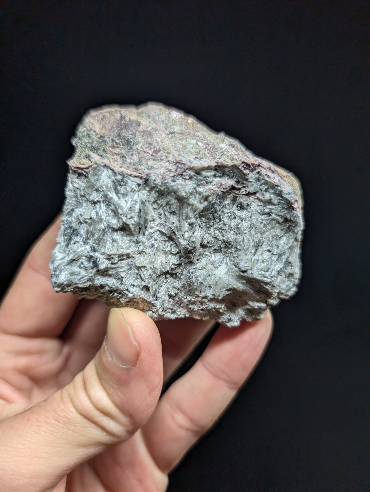 A rough, irregularly shaped gray rock with a textured surface and subtle reddish-brown patches.