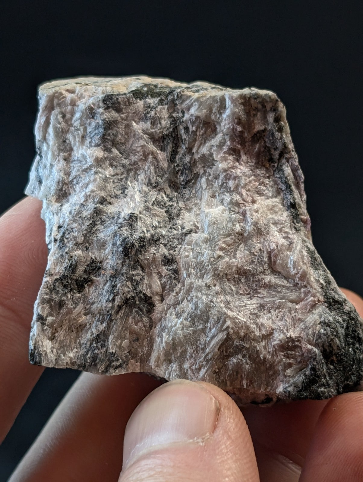 A rough, irregularly shaped piece of mineral with a mottled gray and black surface texture.