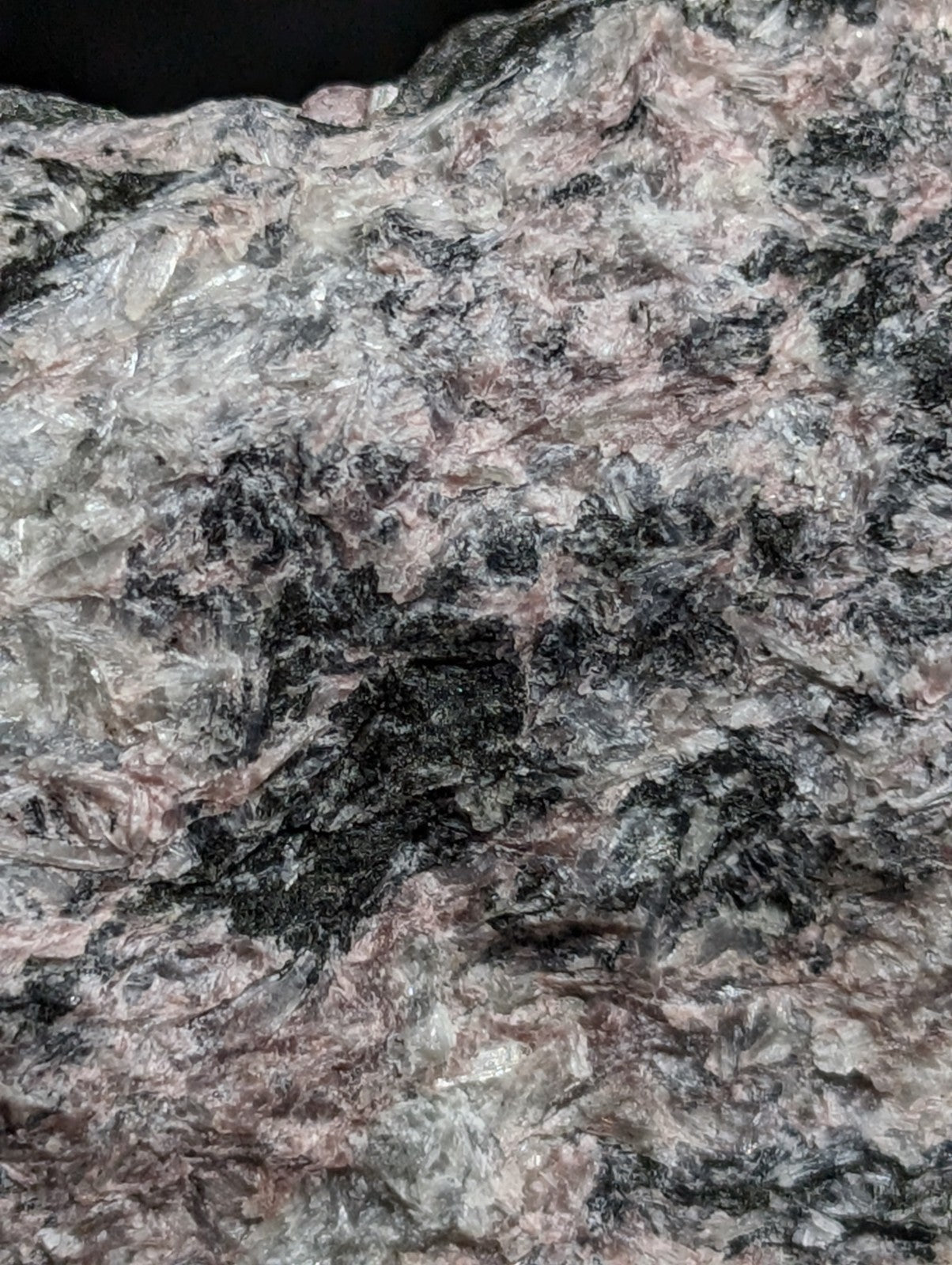 A rugged, naturally occurring rock with a mottled surface of gray, black, and subtle pinkish hues.