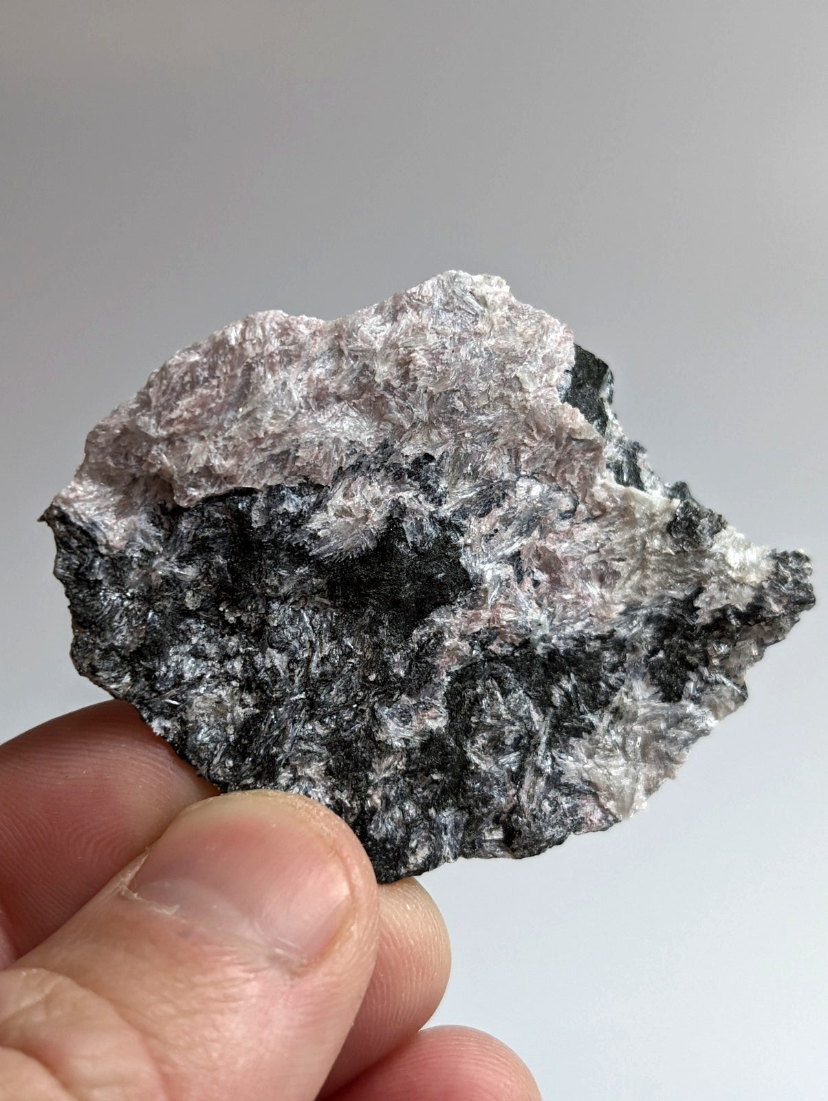 A rough, irregularly shaped mineral specimen with a mottled surface of dark gray and silvery-white patches.