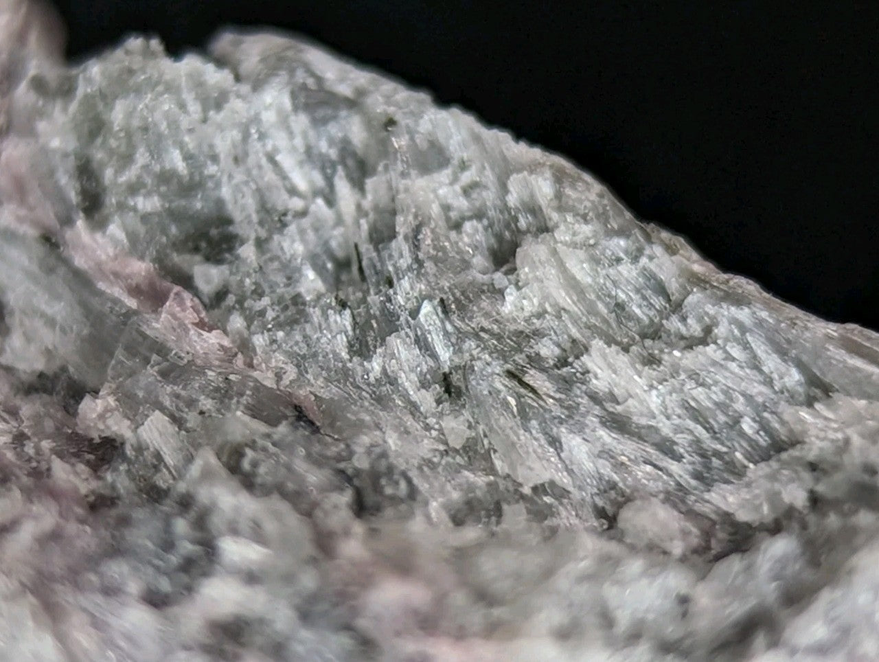 A gray, crystalline mineral specimen with translucent facets and subtle pinkish veining.
