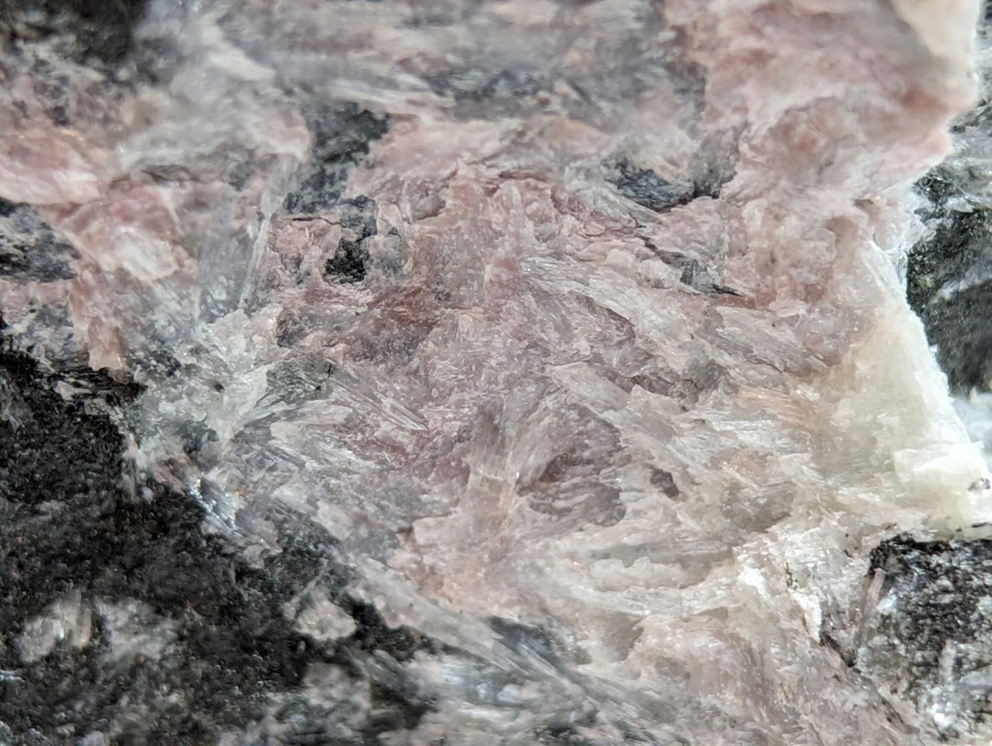 A rough, naturally occurring mineral specimen with a mottled pattern of pinkish-white and dark gray crystalline formations.