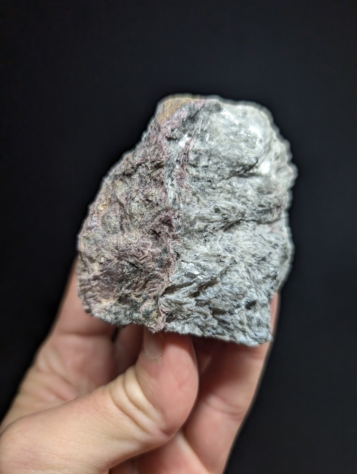 A rough, irregularly shaped rock with a mottled gray and subtle pinkish hue.