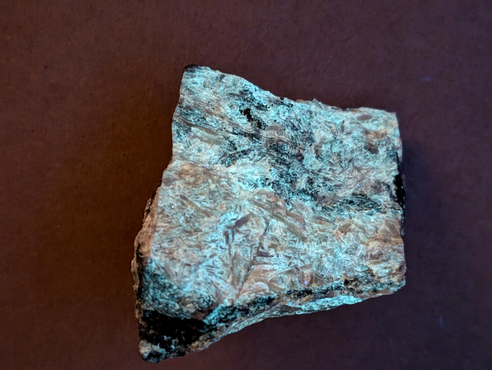 A rough, irregularly shaped mineral specimen with a mottled surface of teal and brownish hues.