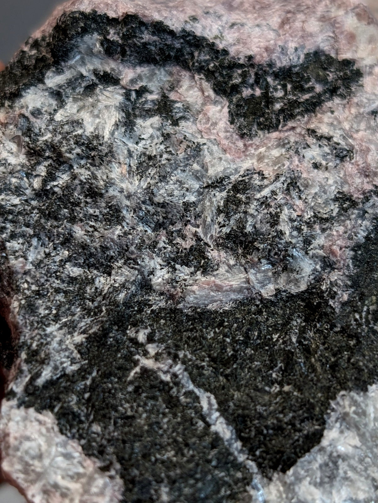 A rugged miserite and wollastonite rock specimen with black gray and pinkish red minerals from wilson springs arkansas