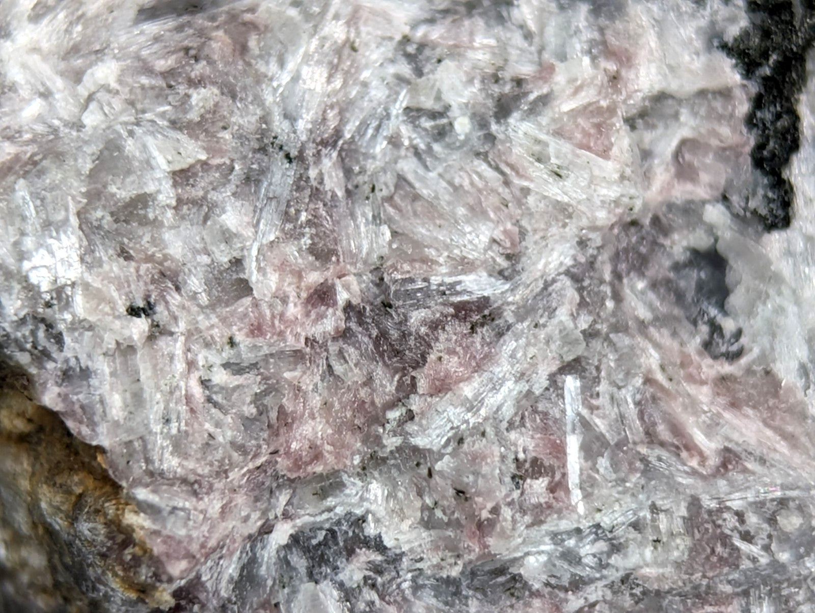 A translucent pink and white crystalline mineral specimen with interwoven, needle-like crystals.