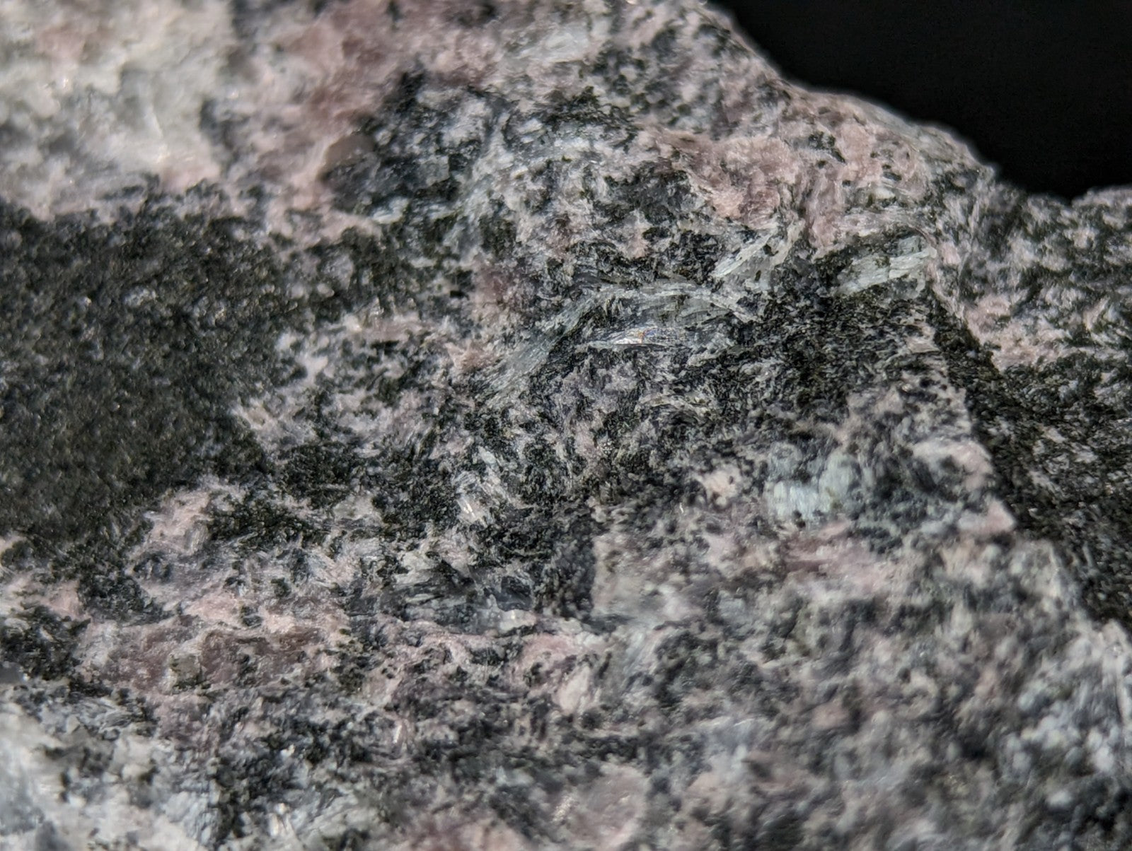 A rugged, speckled granite rock with a mottled pattern of dark gray, black, and pinkish hues.