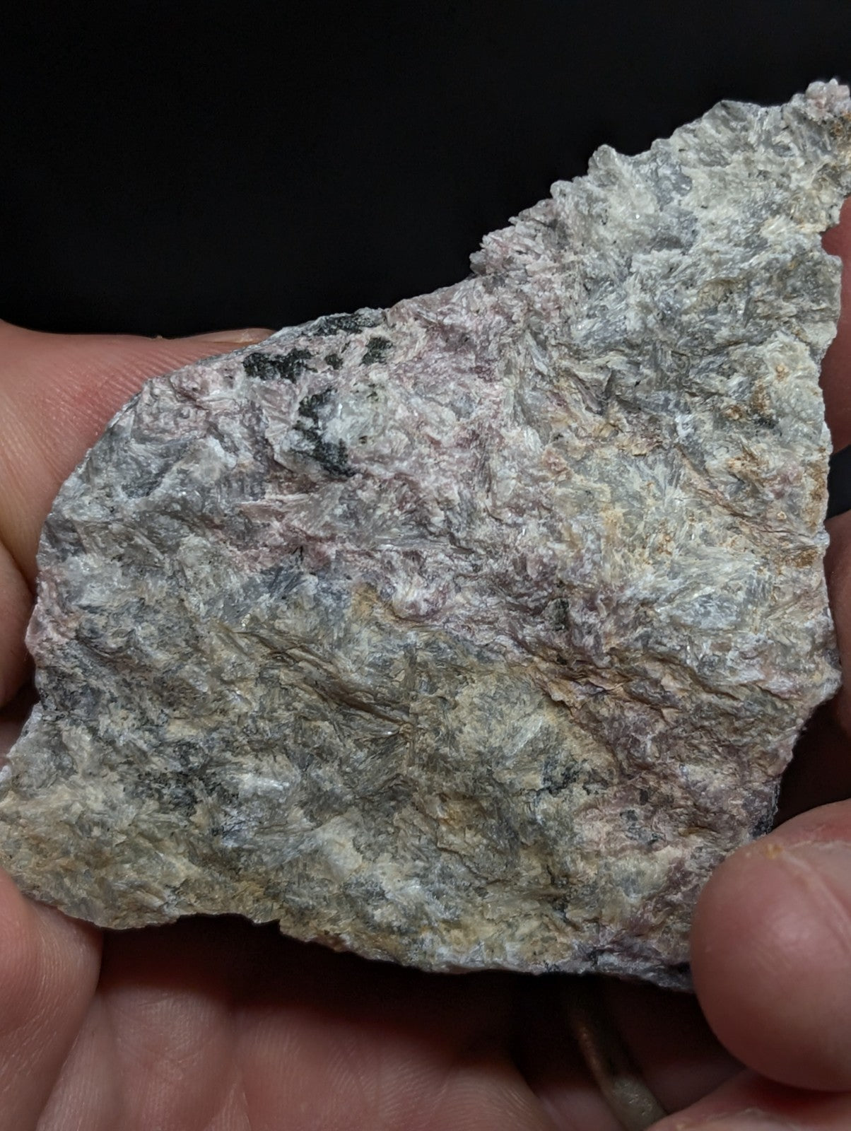 A rough, irregularly shaped stone with a mottled surface of gray, white, and subtle greenish hues.