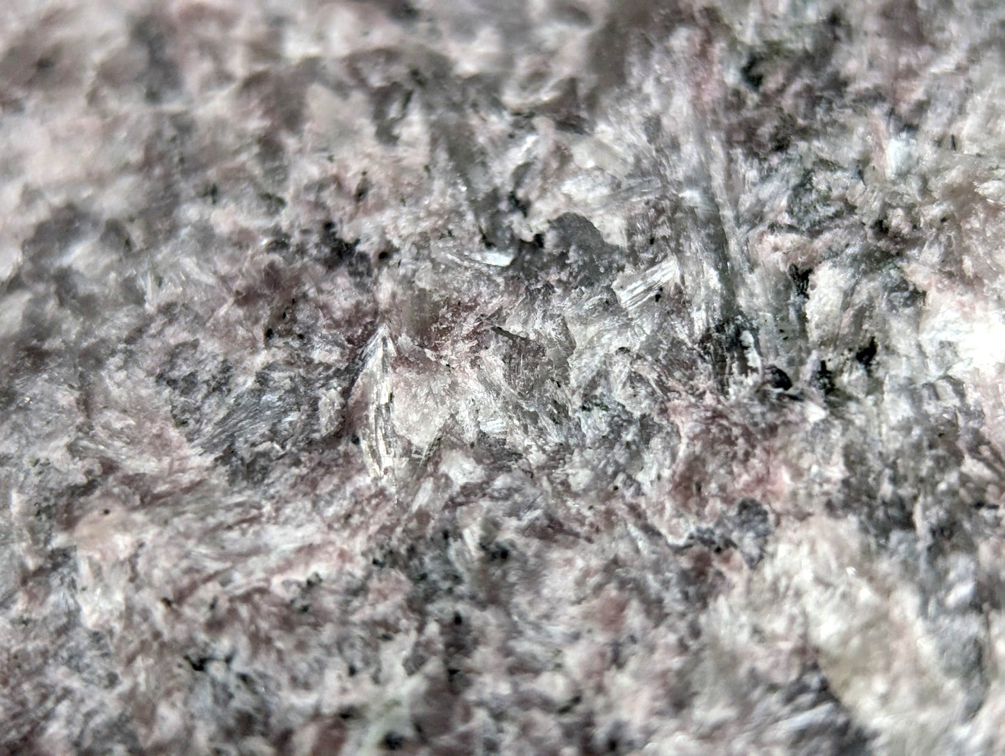 A speckled gray and white granite surface with subtle pinkish undertones.