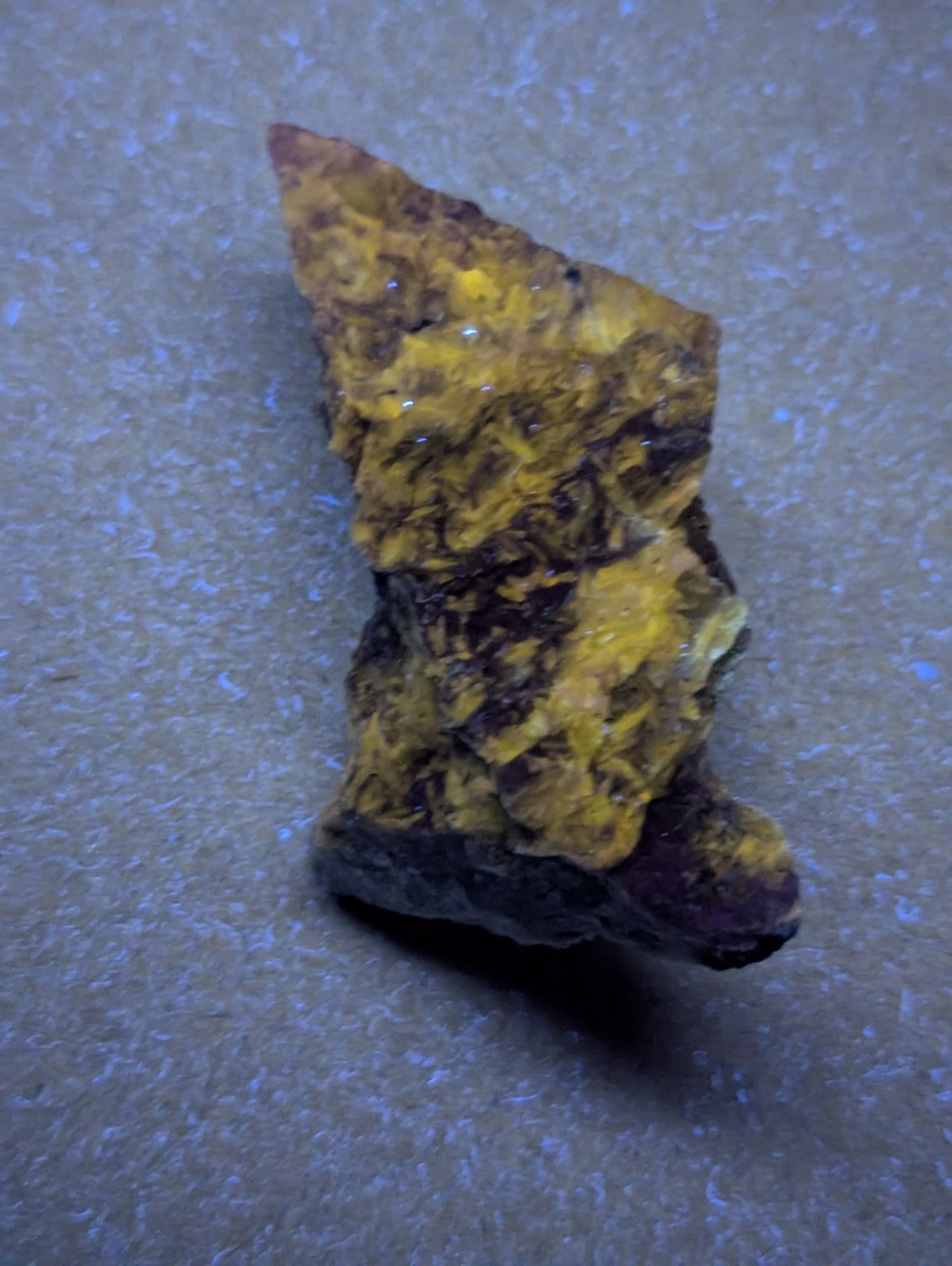 A rugged, irregularly shaped mineral specimen with a vibrant yellow and dark brown mottled surface.