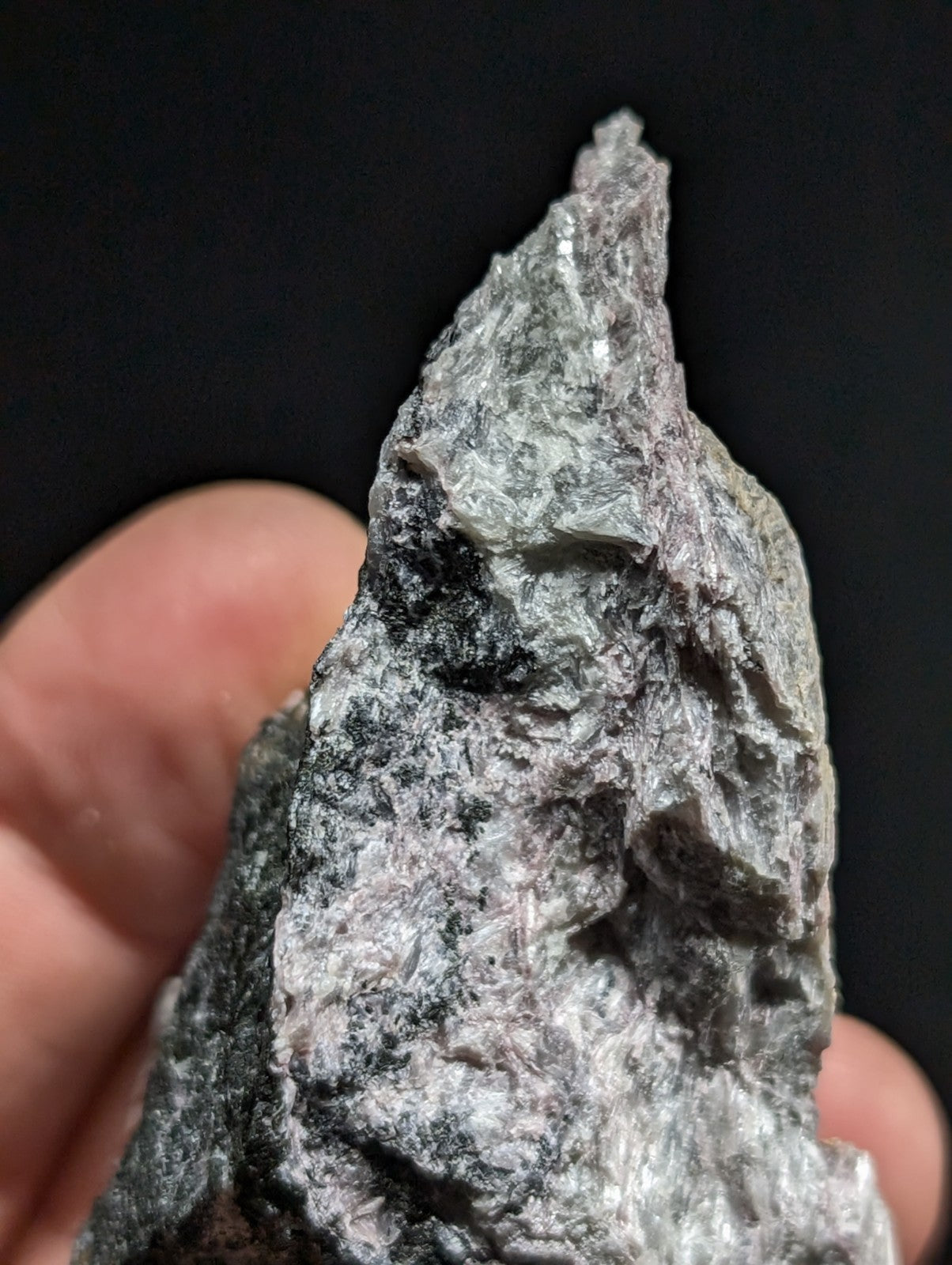 A rough, jagged piece of gray and black mineral with a textured surface.