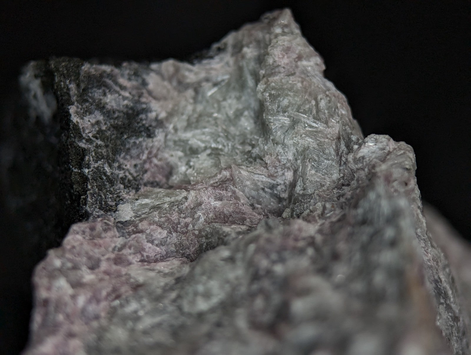 A rough, irregularly shaped mineral specimen with a mottled gray and pale pink surface texture.