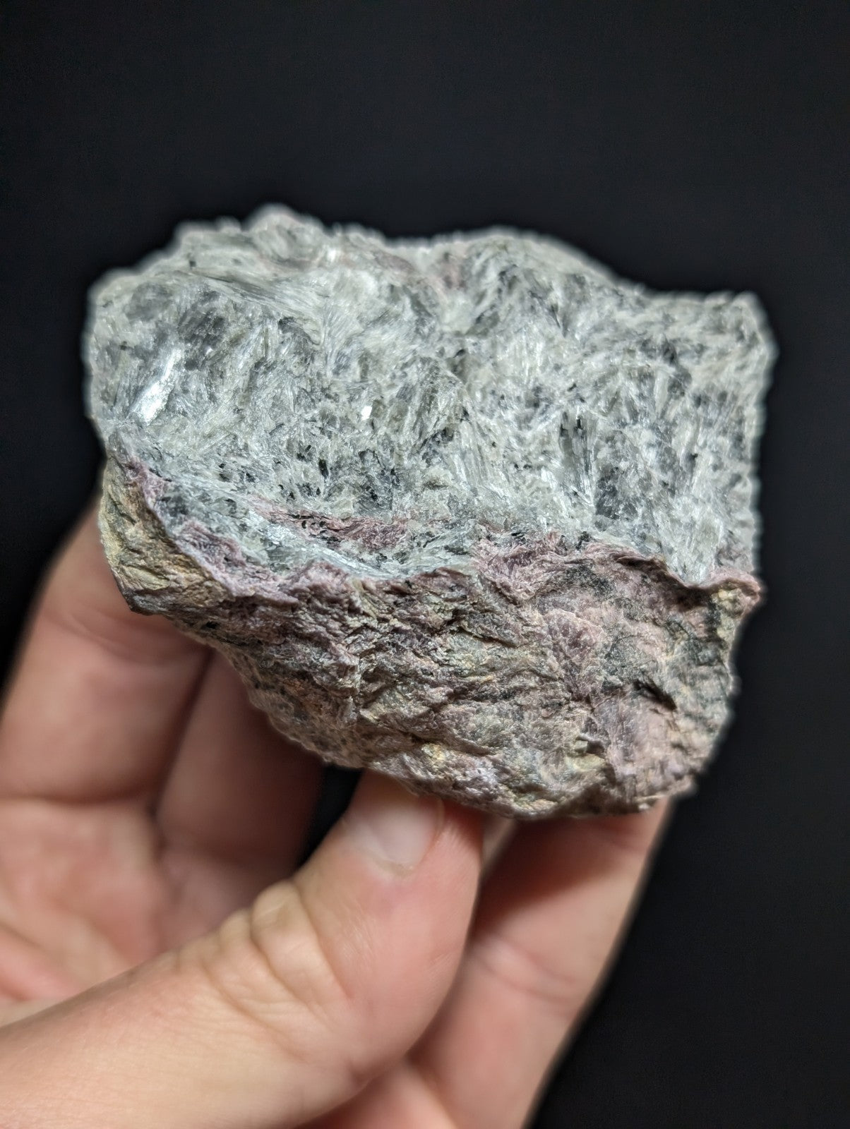 A rough, irregularly shaped mineral specimen with a textured surface displaying shades of gray and subtle pinkish hues.
