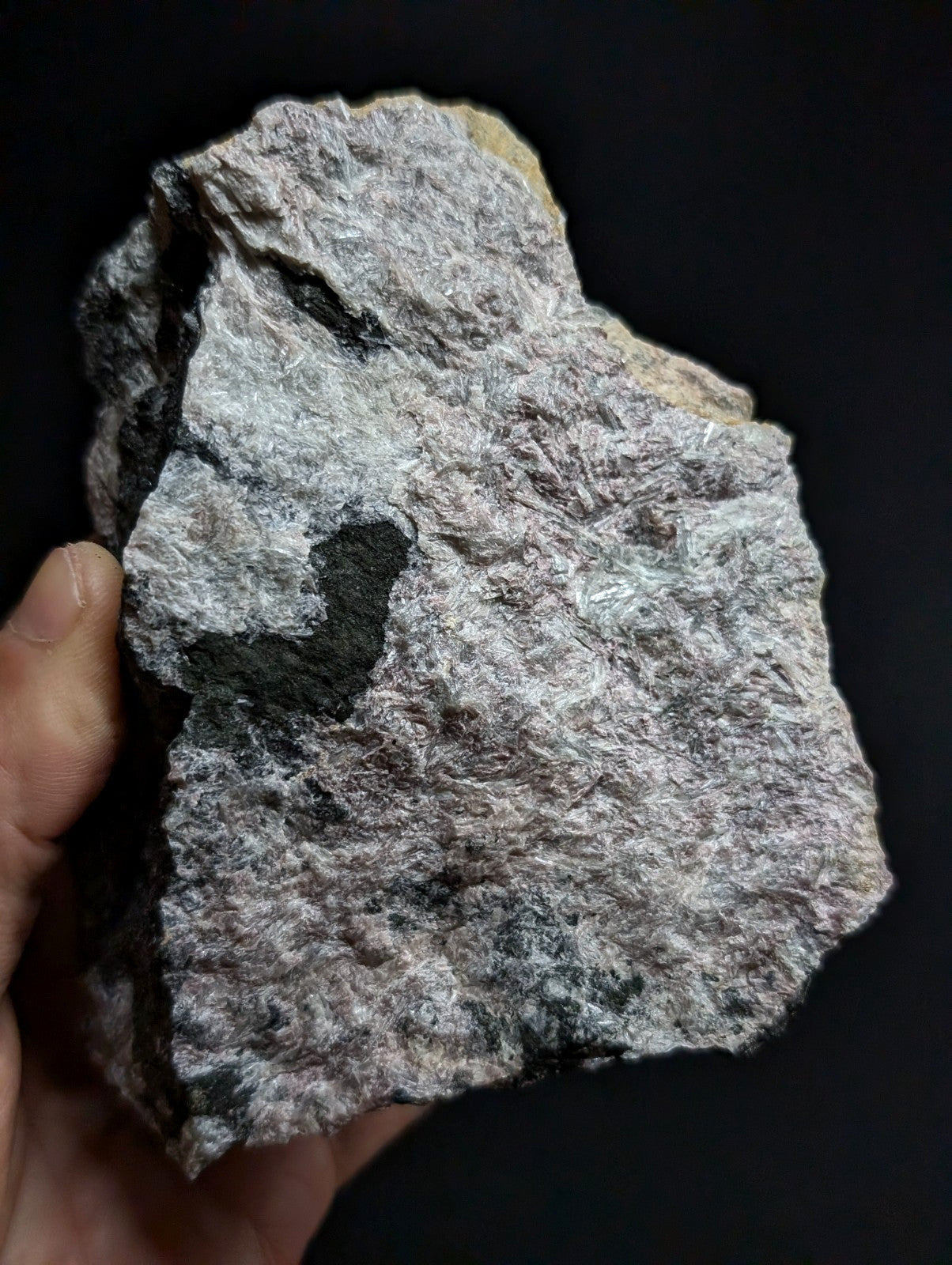 A rough, irregularly shaped rock with a mottled gray and black surface featuring subtle greenish veining.