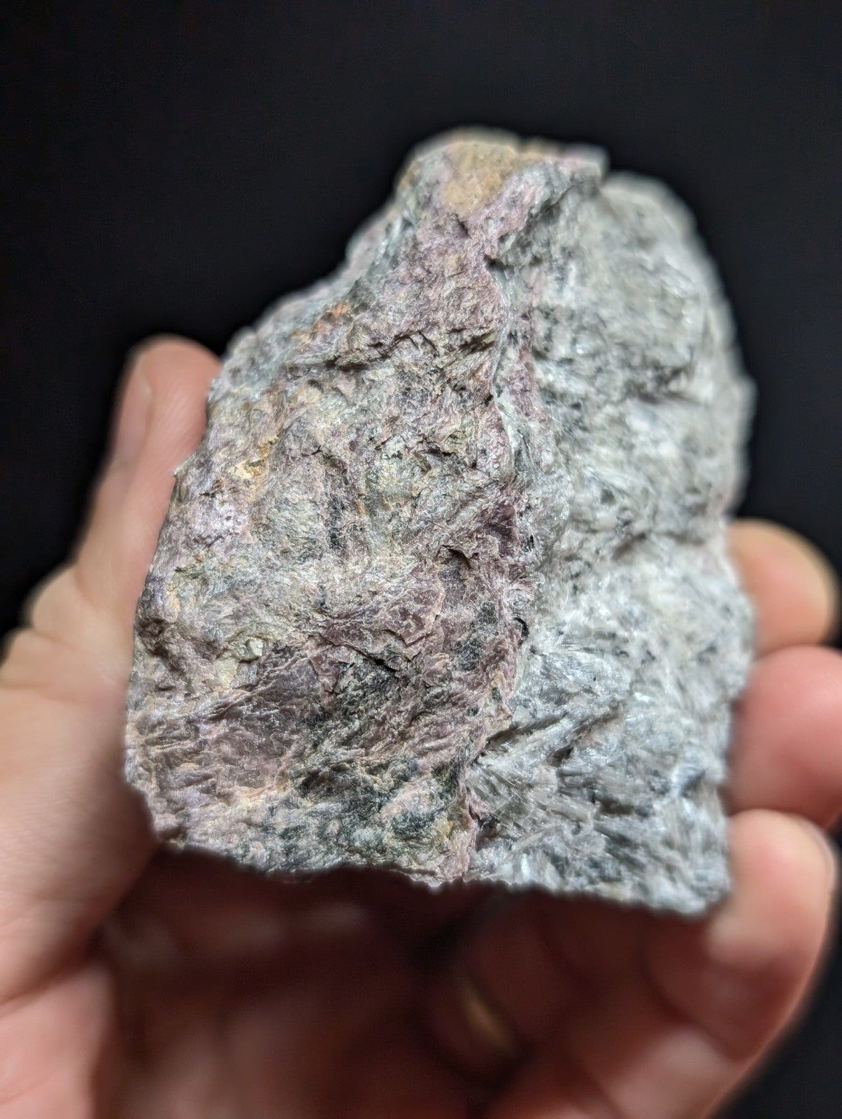 A rough, irregularly shaped stone with a mottled gray and pinkish hue.