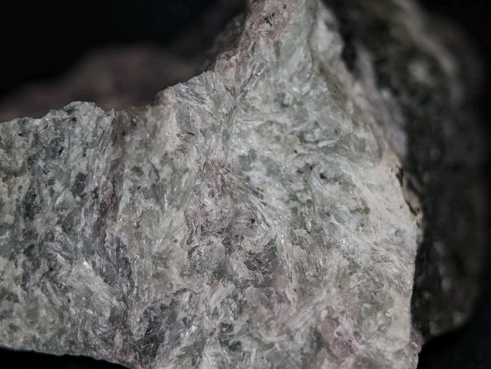 A rough, grayish-white rock with a crystalline texture and subtle pinkish undertones.