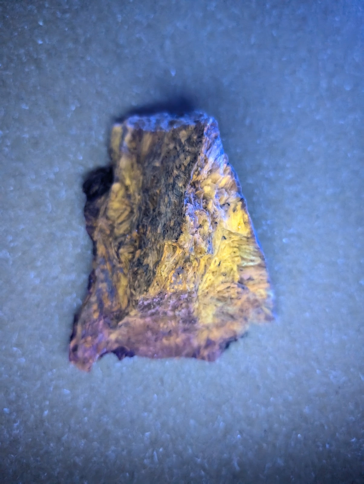 A rugged, irregularly shaped piece of golden-yellow and dark brown mineral with a rough, textured surface.