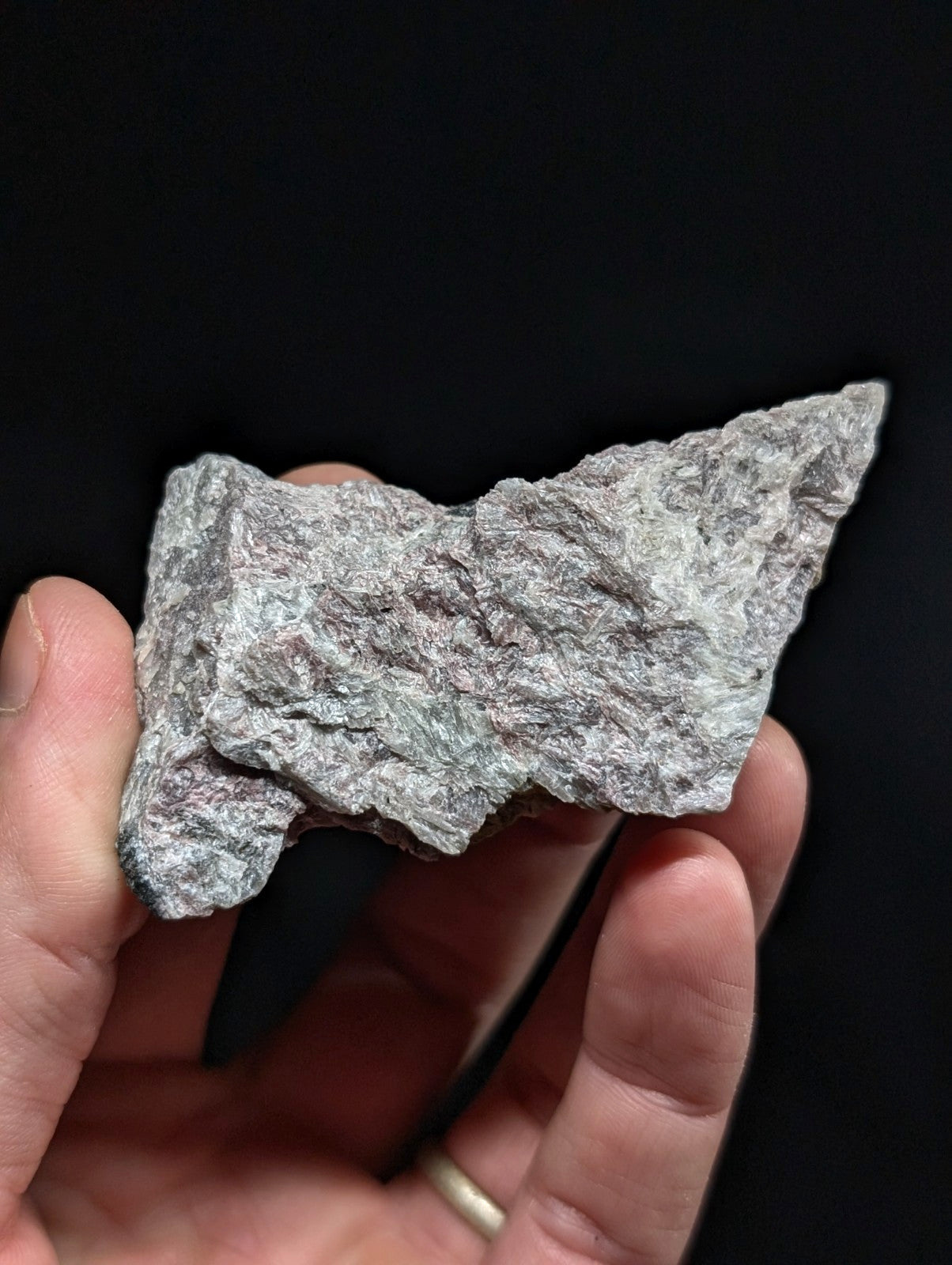 A rough, grayish-green stone with a textured surface and irregular edges.