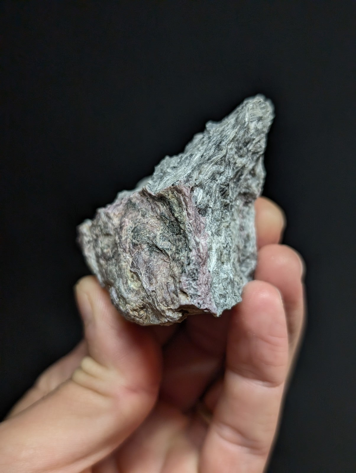 A rough, irregularly shaped mineral specimen with a mottled gray and subtle pinkish hue.