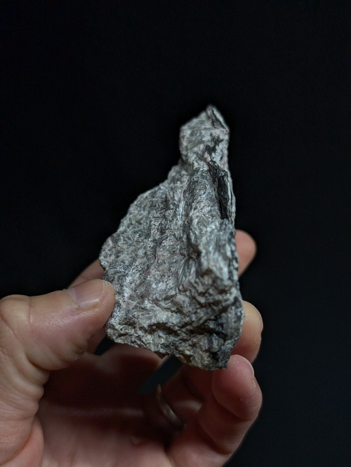 A rough, irregularly shaped gray rock with a speckled texture and natural fissures.