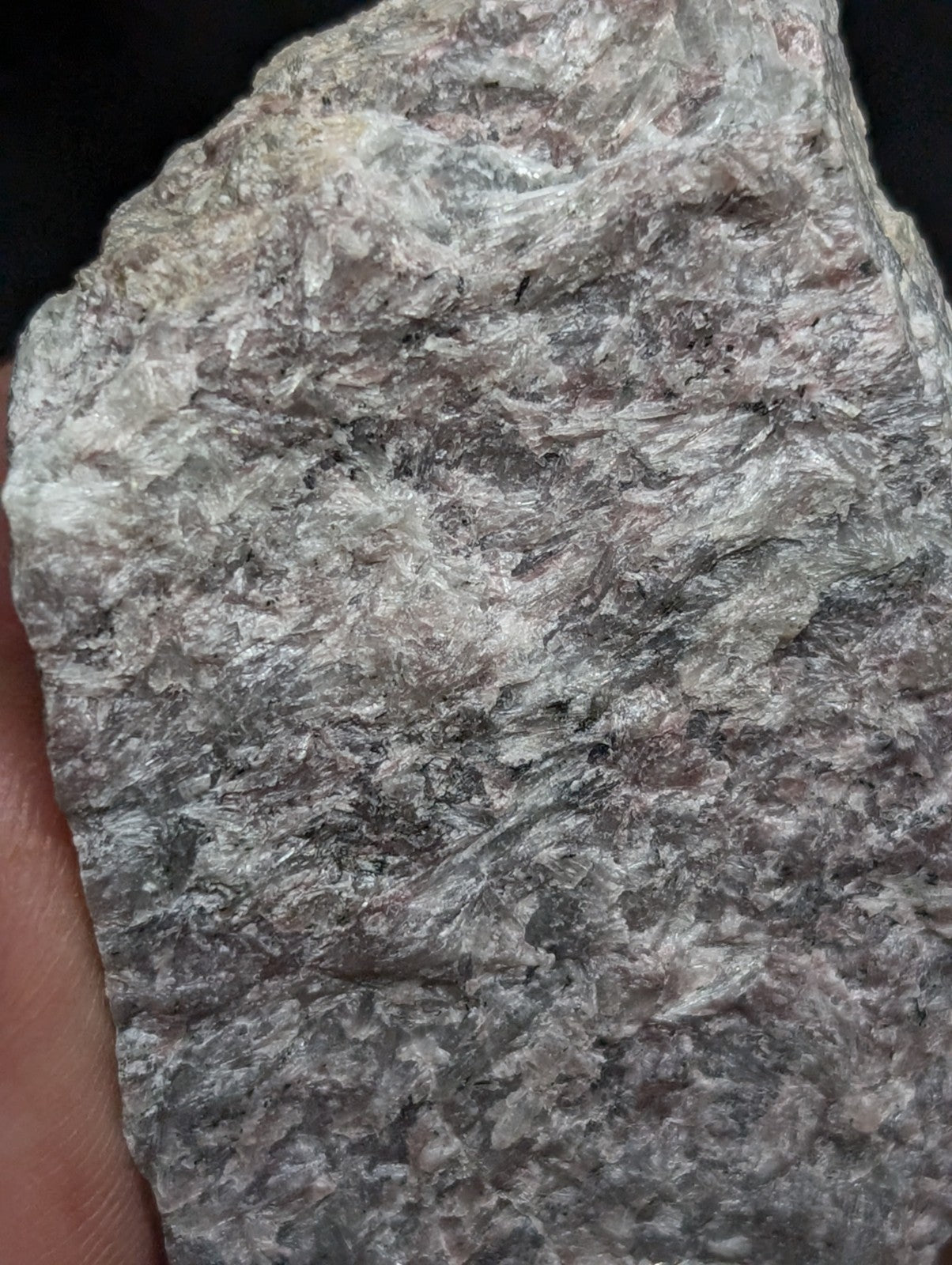 A rough, irregularly shaped gray rock with a mottled texture and subtle hints of white and darker mineral streaks.